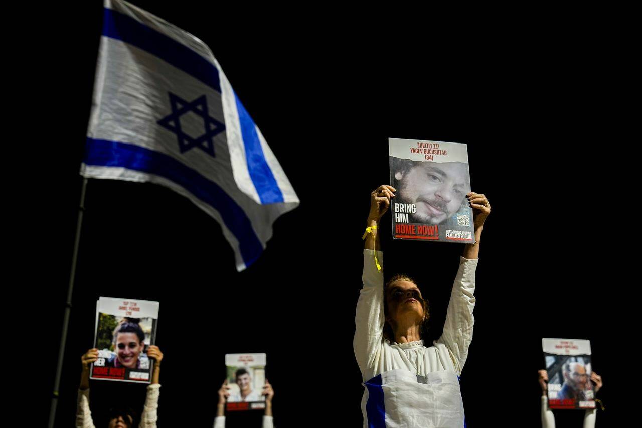 Families and supporters of Israeli hostages held by Hamas in Gaza hold their photos and shout slogans during a rally calling for their release, in Tel Aviv, Israel, Saturday, Dec. 30, 2023. More than 100 Israeli hostages are held in Gaza after being abducted in a Hamas cross-border attack on Oct. 7. (AP Photo/Ariel Schalit)