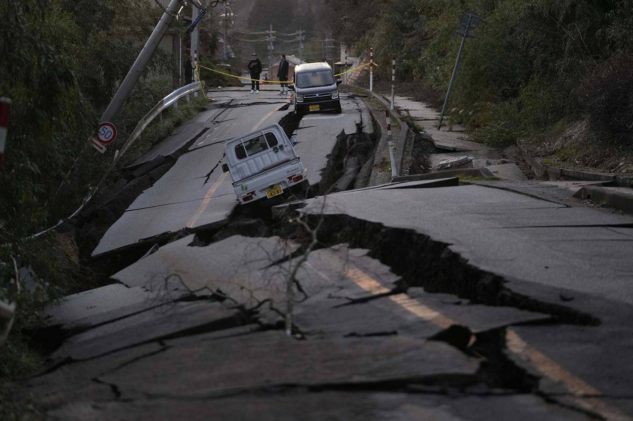 Bystanders look at damages somewhere near Noto town in the Noto peninsula facing the Sea of Japan, northwest of Tokyo, Tuesday, Jan. 2, 2024, following Monday’s deadly earthquake. A series of powerful earthquakes that hit western Japan have damaged thousands of buildings, vehicles and boats. Officials warned that more quakes could lie ahead. (AP Photo/Hiro Komae)