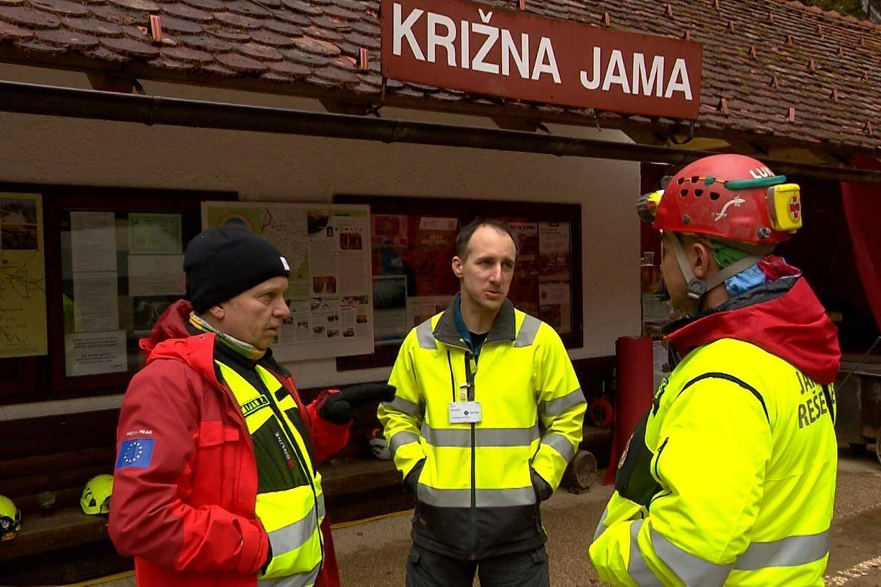 In this photo taken from video, rescuers gather outside the Krizna Jama cave near Grahovo, Slovenia, Sunday, Jan. 7, 2024. Slovenian authorities say five people are trapped in a cave in the southwest of the country because of high water levels caused by heavy rainfall. The group includes a family of three and two guides who have been stuck in the Krizna Jama cave since Saturday when water levels rose inside, blocking the way out. (Pop TV via AP)