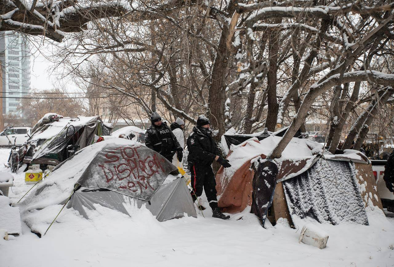 An editor with an online media outlet says Edmonton police have arrested one of his reporters as they broke up a homeless encampment in the city. Police inspect a homeless encampment as residents and supporters have a stand off as police prepare to clear homeless encampments in Edmonton, Tuesday, Jan. 9, 2024. THE CANADIAN PRESS/Jason Franson.