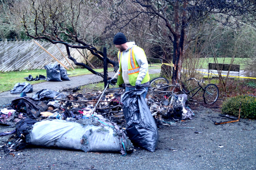 A Sooke municipal worker cleans up after a fire at a homeless encampment in Sooke last weekend. (Rick Stiebel - Sooke News Mirror)